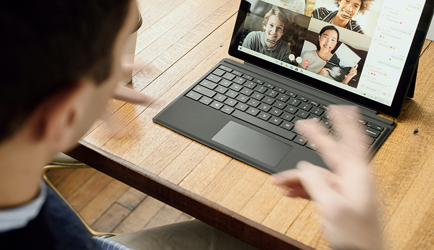 Person in front of a laptop with digital meeting gallery view of several faces