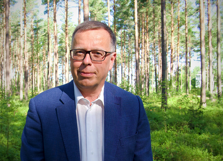 Porträtt på Anders Brolin med tallskog i bakgrunden.