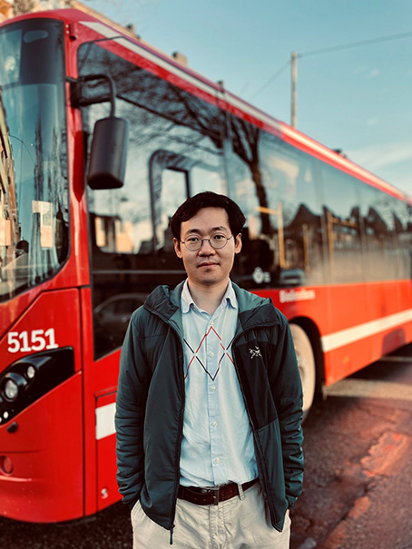 Student framför en röd buss. 