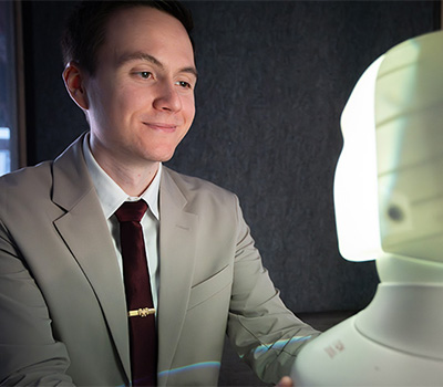 John Sinderwing framför en ljus profil av en robots ansikte