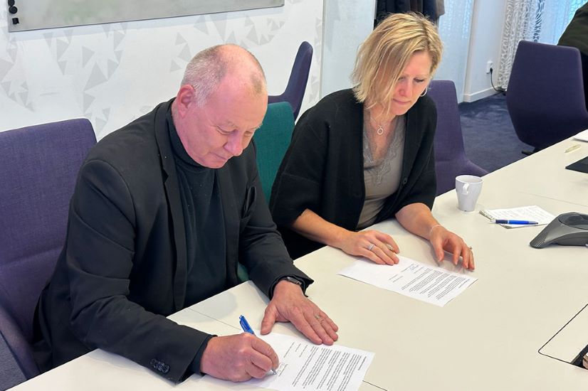 Two persons sitting at a table signing an agreement.