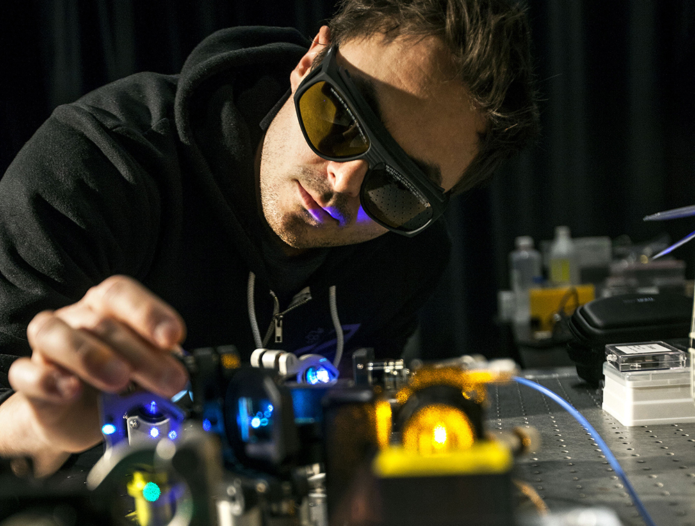 Man med skyddsglasögon använder forskningsutrustning i labbet Advanced Light Microscopy.