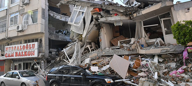 Rasmassor efter en jordbävning. Ett hus som kollapsat över en bil.
