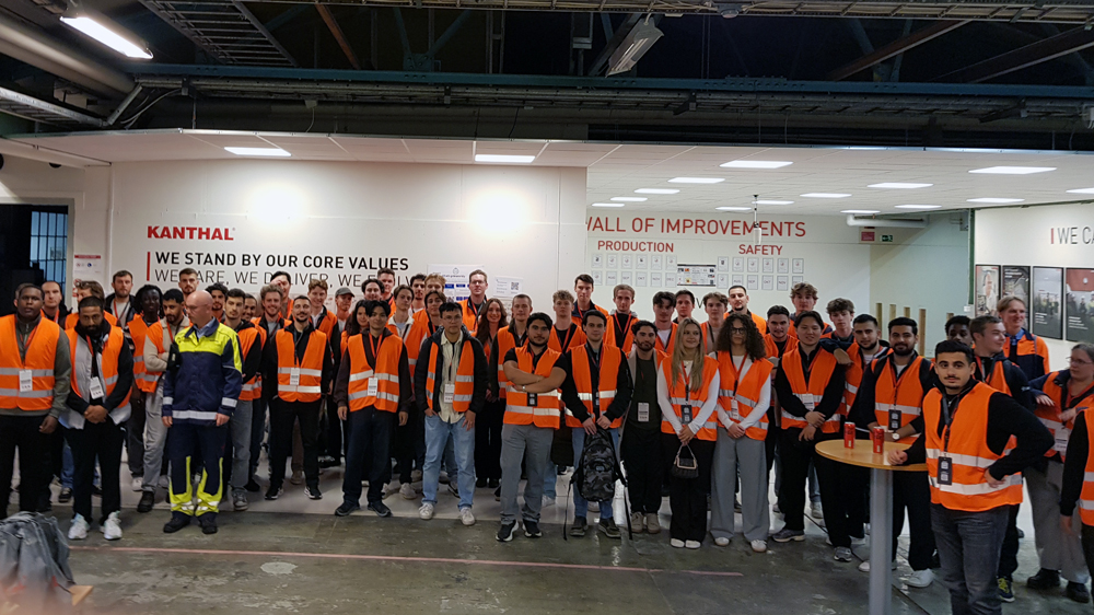 A group of students in orange vests in industry building.
