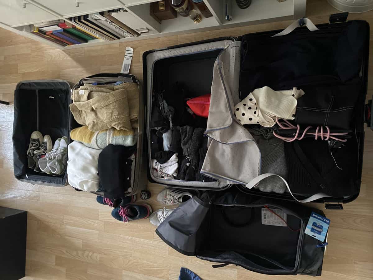 Två öppna resväskor på golvet med kläder i. 