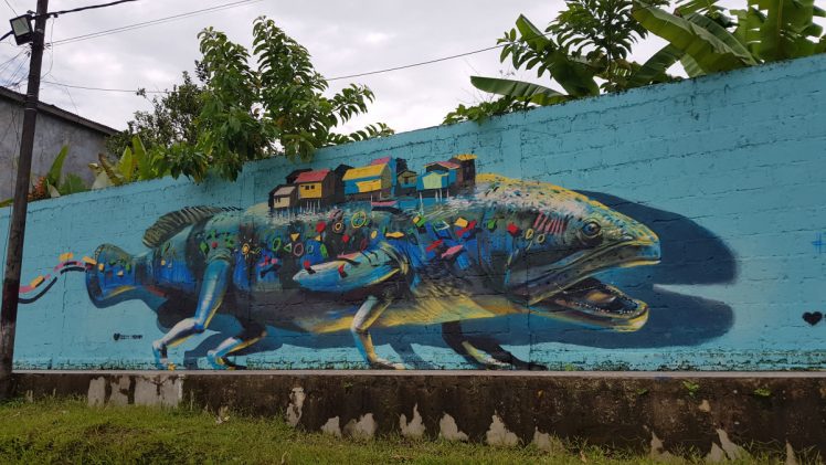 Mural painting depicting a fish human hybrid animal with houses on it's back