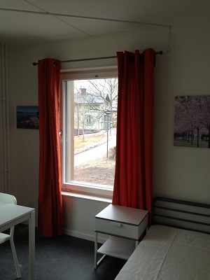 90 cm bed in white painted apartment with window and orange curtains.