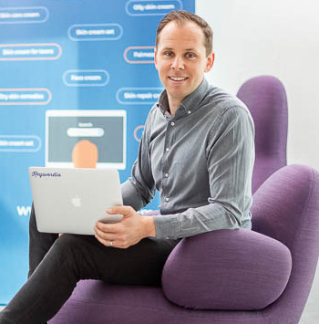 Jonas Hagströmer Theodorsson sitter i en fåtölj med en laptopdator i knät