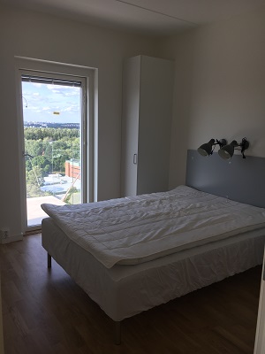 Bed in white painted room with door out to sunny balcony.