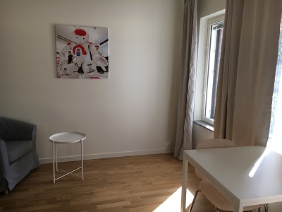 Studio apartment with picture on wall, armchair, table and two chairs.