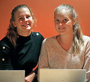 Foto på Kemistudenterna Madeleine Vikström och Jenny Blomgren som sitter bakom varsin bärbar dator.