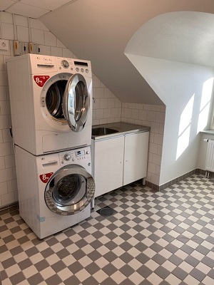 Stacked washer and dryer in tiled laundry room.