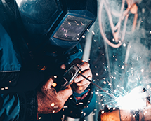 A man who's welding with sparks flying around.