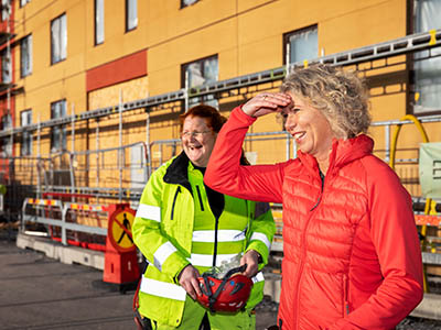 Annika Vänje tillsammans med byggnadsarbetare Mira Fred utomhus på byggarbetsplats