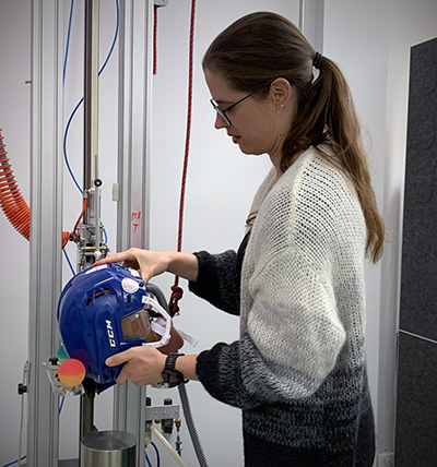 En forskare, Madelen Fahlstedt, monterar en hjälm på en testställning.