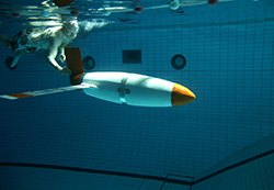 Man swimming underwater in a pool with an automated underwater vehicle