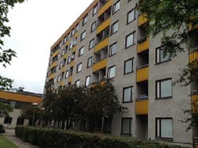 Outdoor photo of building made from concrete with yellow balconies.