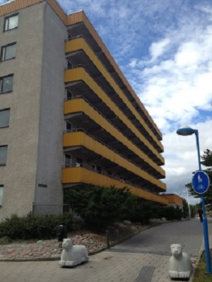 Outdoor photo of building with concrete and yellow balconies.