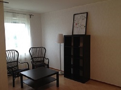 Apartment with window, bookshelf, two chairs and coffee table.
