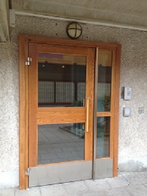 Wooden and glass front door of building with key pad.