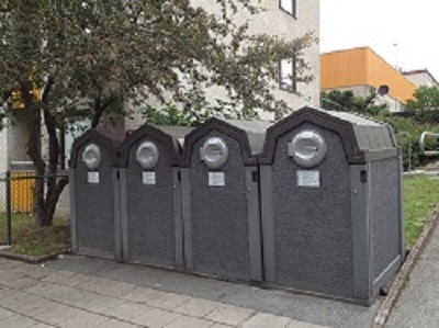 Four garbage bins lined up outdoors with hatches to open them.