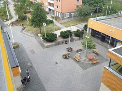 Photo taken from highest balcony looking down on square, plants and subway entrance.