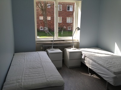 Blue painted bedroom with two 90 cm beds, window, nightstands and lamps.