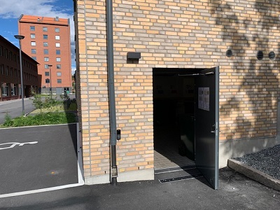 Door open to recycling room in light beige brick building