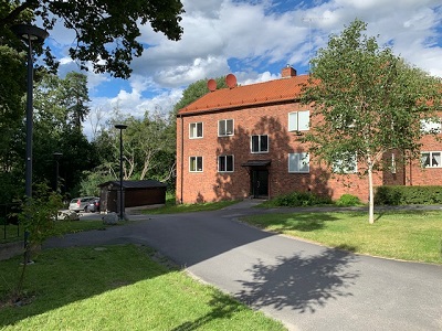 Red brick building with trees and grass.
