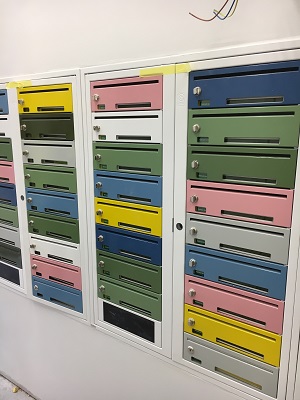 Colorful mailboxes built into wall, with mailslots in them.