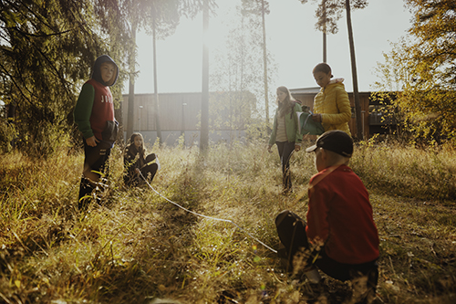 Children measuring in the woods with the sun in the background