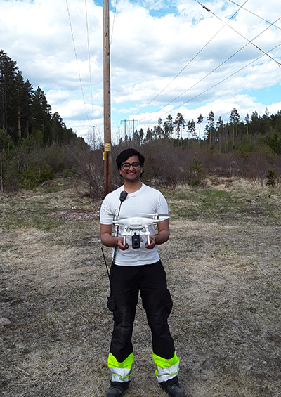 Umar Chughtai holding inspection drone in field where power lines are 