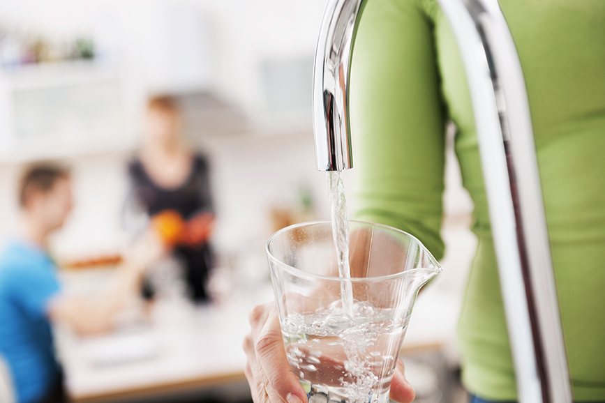 En person håller ett glas under en vattenkran med rinnande vatten.