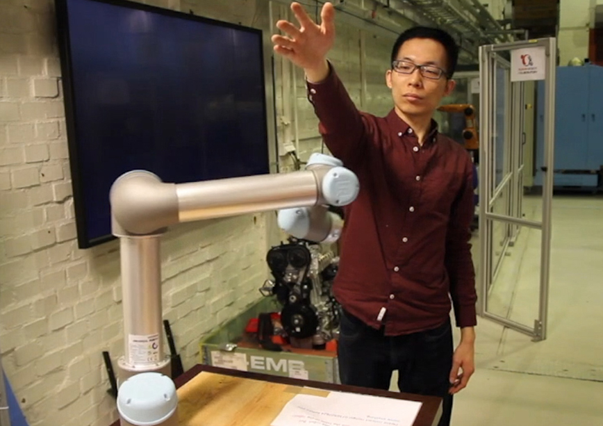 Hongyi Liu tests a robot arm by placing his hand in its path. 