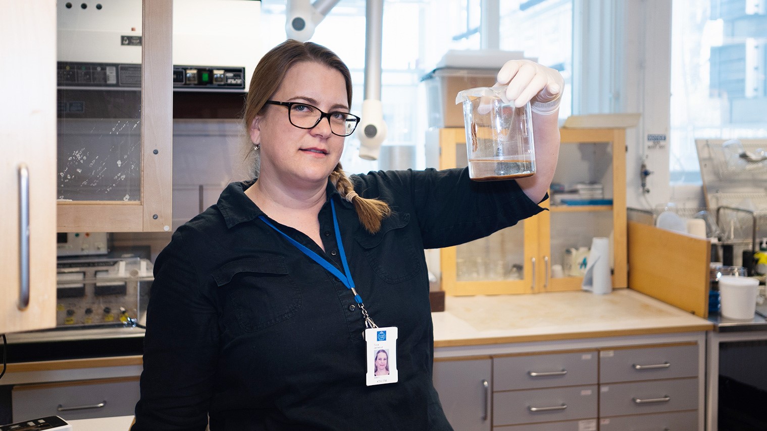 Kvinna i labb som håller labbglas
