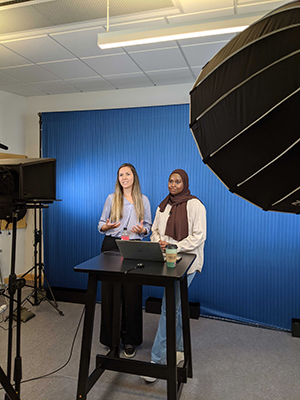 Two women in a studio setting, with lights and cameras. 