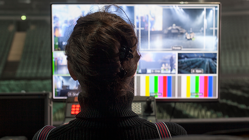 woman facing computer screen in control room at shipping terminal