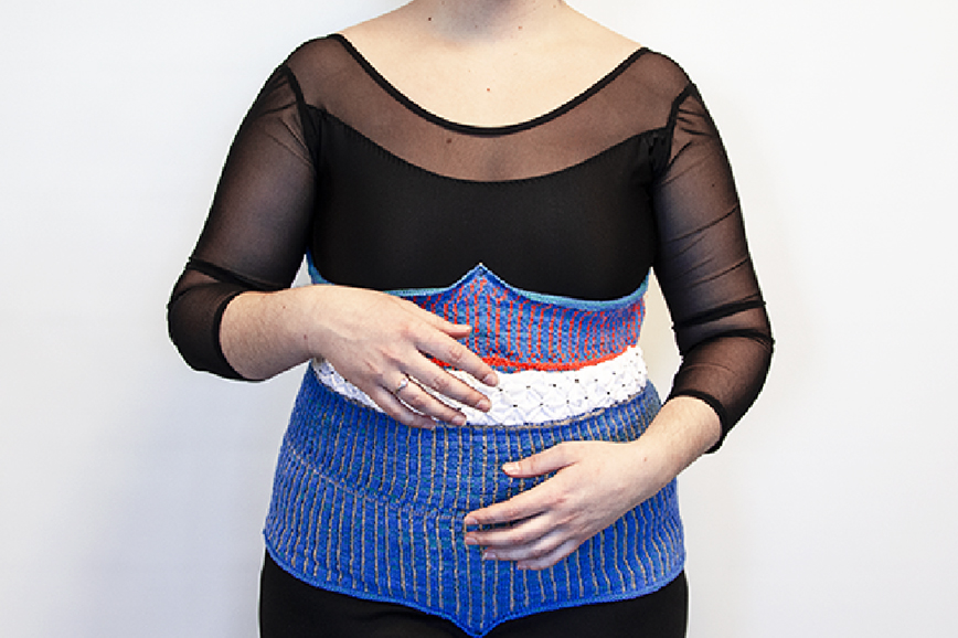 A model wearing a knitted upper body garment with robotic features.