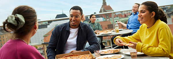 En grupp studenter som äter pizza på Arkitekthusets takterass på KTH