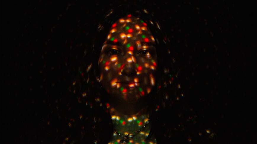 Porträttbild på kvinna med lysande färger i ansiktet. 