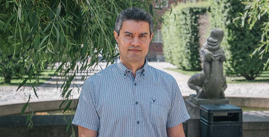 Portrait of Rustam Nabiev on KTH Campus. Trees and brick building in the background.