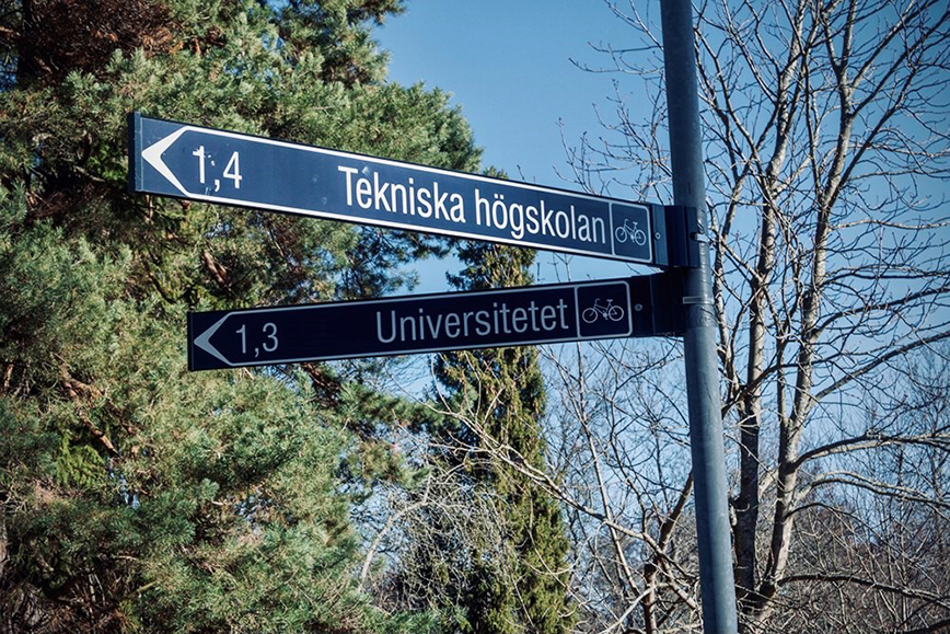 Vägskylt som visar riktningarna mot ett universitet och en teknisk högskola.