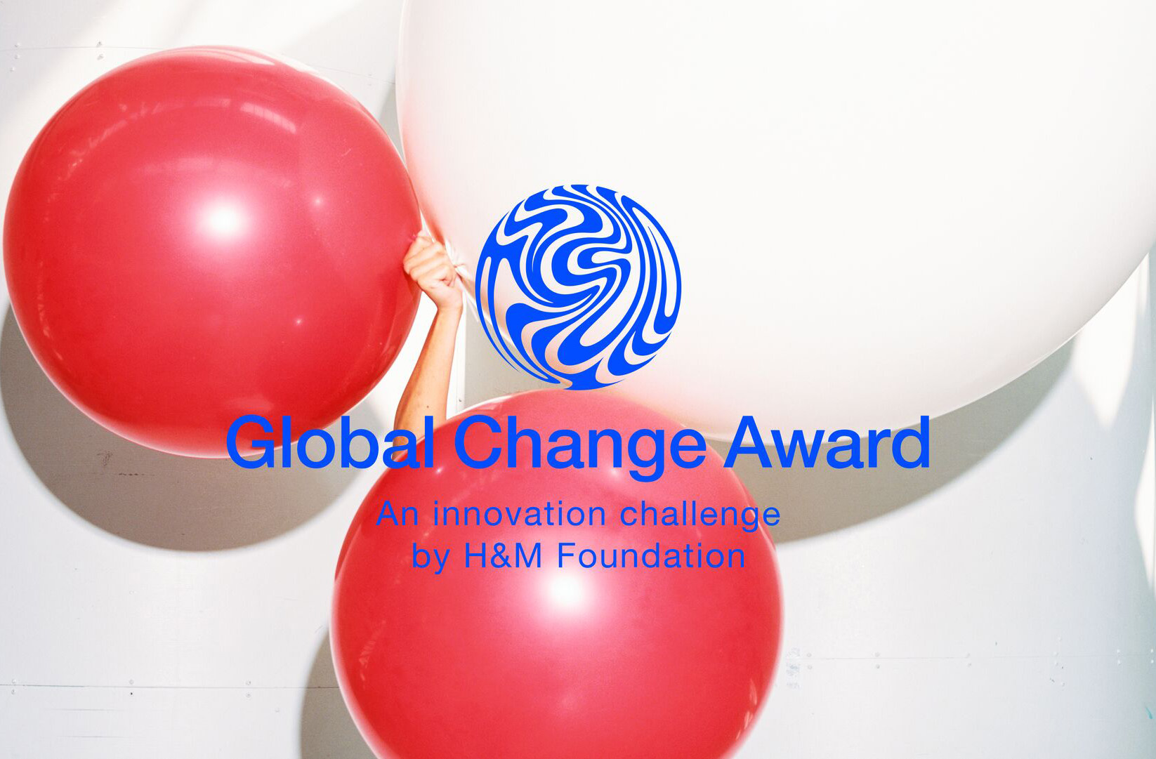 Arm holding three large balloons in white and pink. Global Change Award in blue text on top.