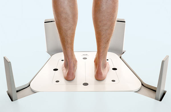 A person standing on a foot scanner. We see the legs up to the knees.
