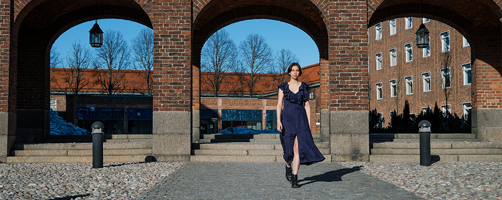 Woman in blue dress walking in front of brick archways