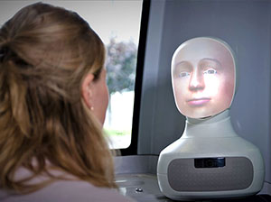A robot head talks to a passenger aboard a bus