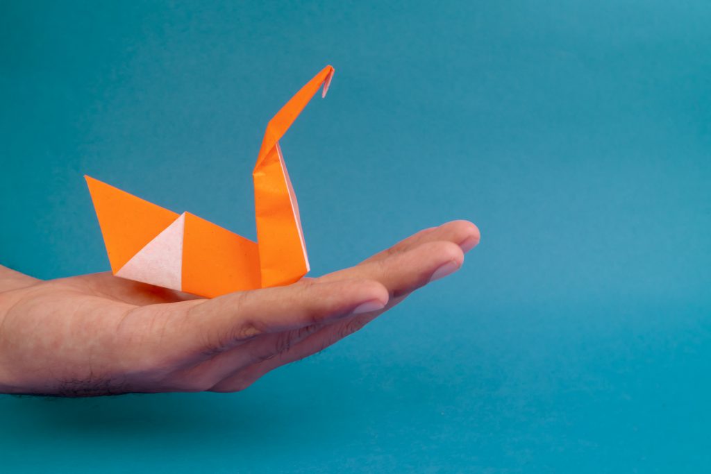 En hand som håller i en origamifågel