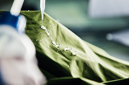 A drop of water rolls down a green jacket