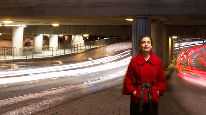 Kvinna i röd jacka framför två vägar.