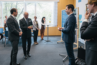 Prince Daniel and the King look at iPercept's product, a small green box. The founders look on.